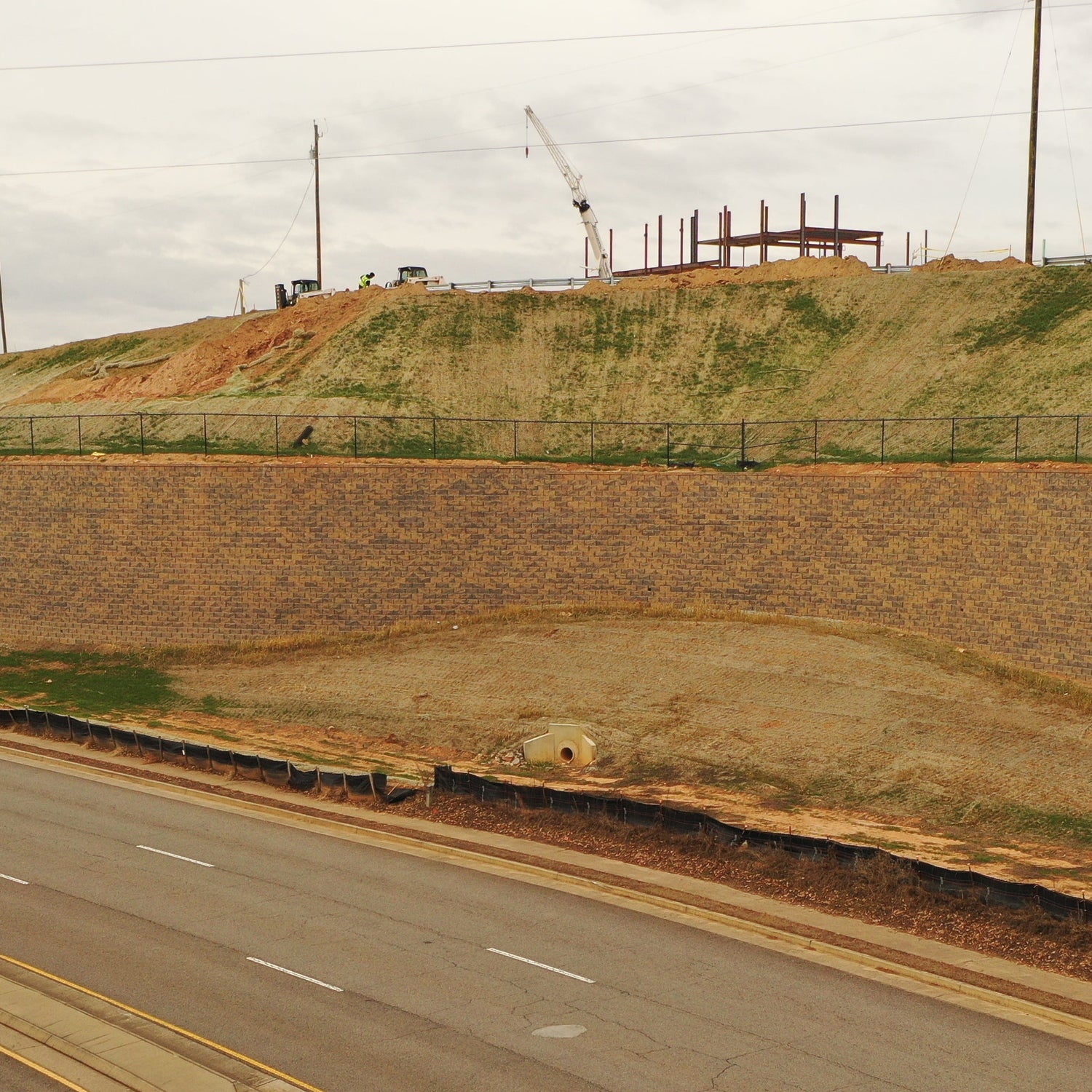 Retaining wall adjacent to a road with construction site in the background.